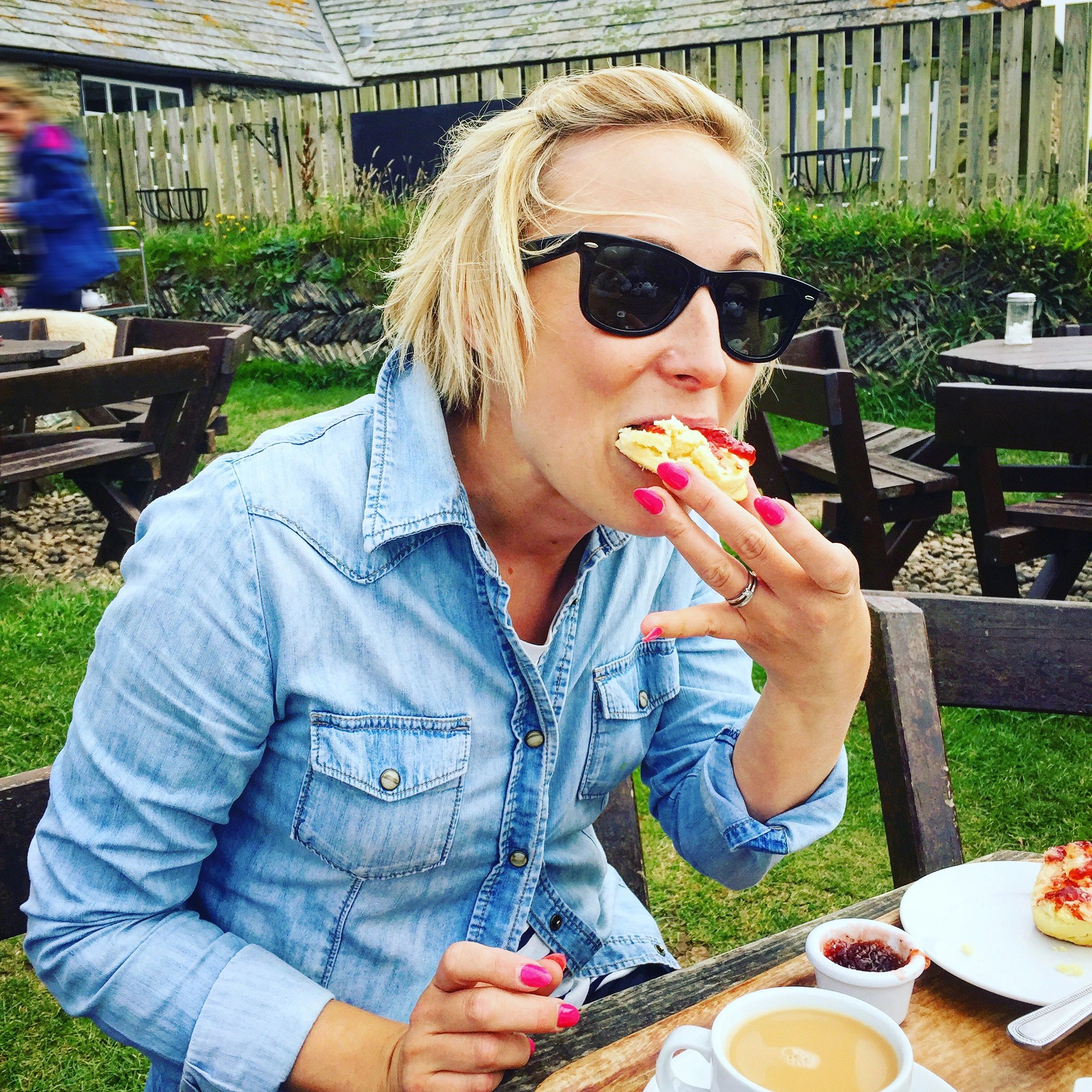 Person enjoying tea and scones at a table
